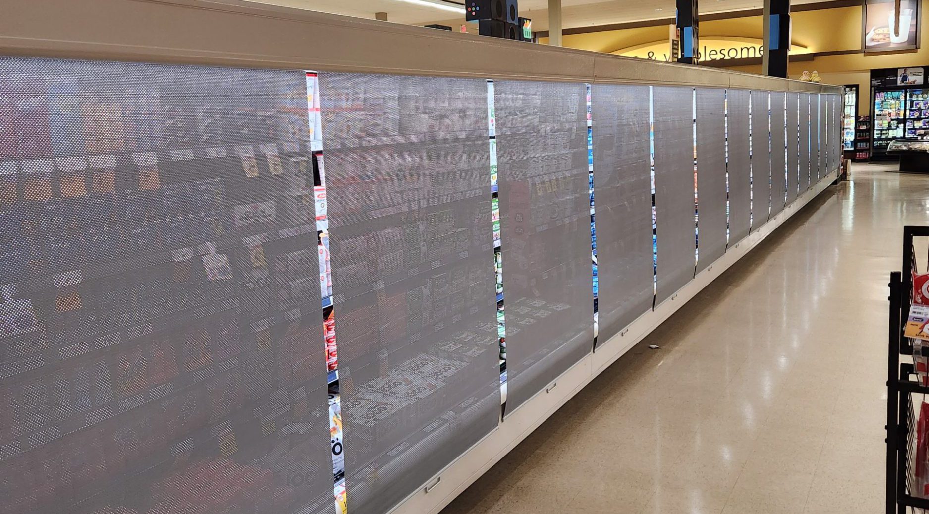 Grocery store refrigeration aisle with night curtains closed to save energy.
